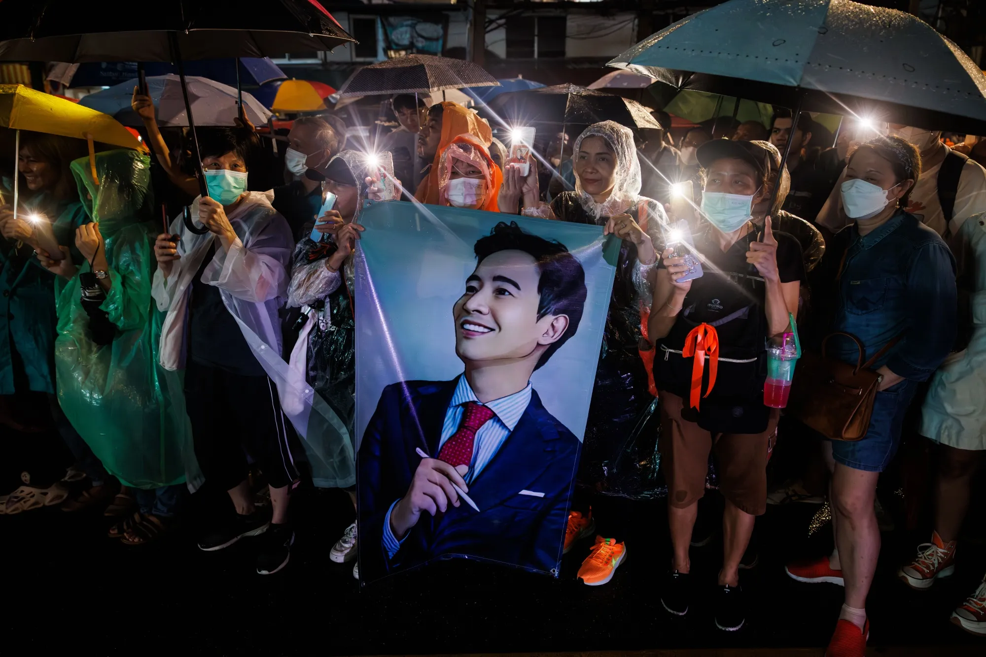 Protesters hold up the three-finger salute and a portrait of Pita Limjaroenrat during a protest in Bangkok on July 23.