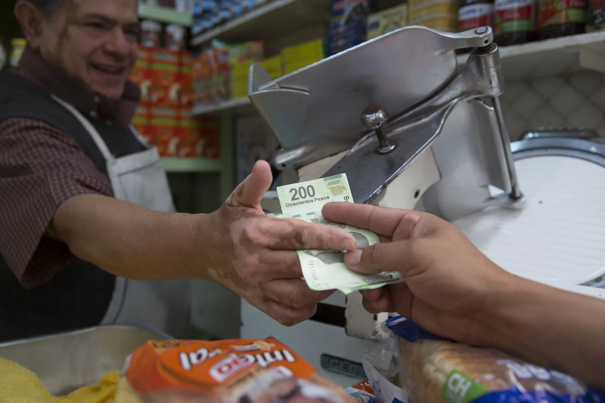 A customer exchanges Mexican pesos for goods at the Medellin market in Mexico City