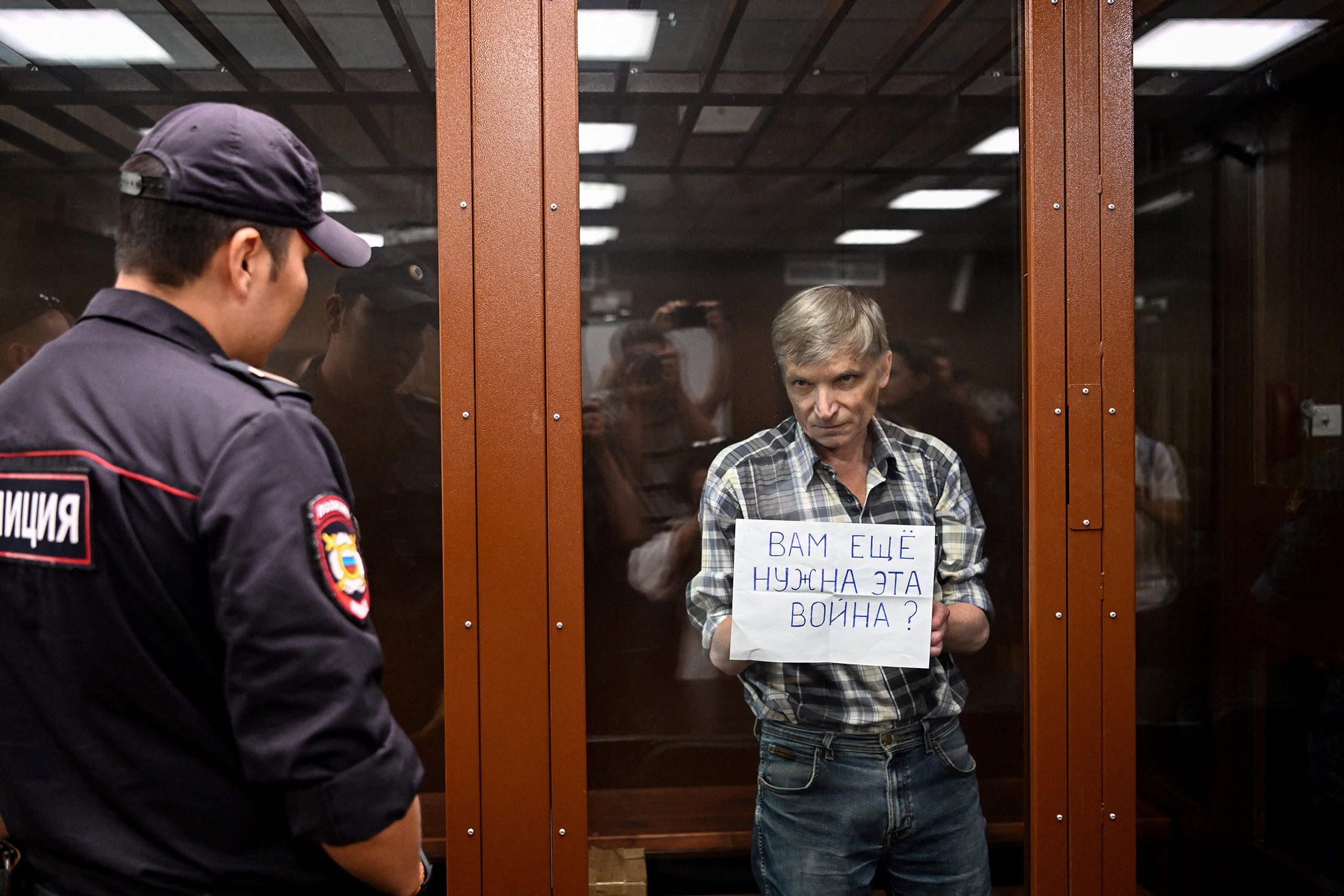 Alexei Gorinov holds a sign reading “Do you still need this war?” inside a glass cell during the verdict hearing in his trial at a courthouse in Moscow on July 8.