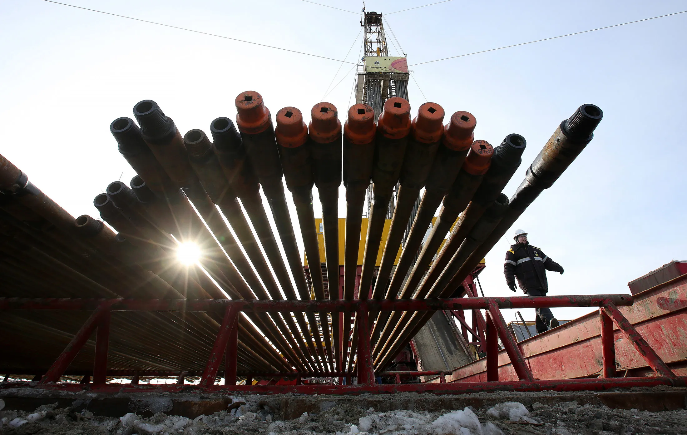 A worker passes an oil drilling rig and drill pipes, operated by Rosneft PJSC, in the Samotlor oilfield near Nizhnevartovsk, Russia, on Tuesday, March 21, 2017. Russia's largest oil field, so far past its prime that it now pumps almost 20 times more water than crude, could be on the verge of gushing profits again for Rosneft PJSC.
