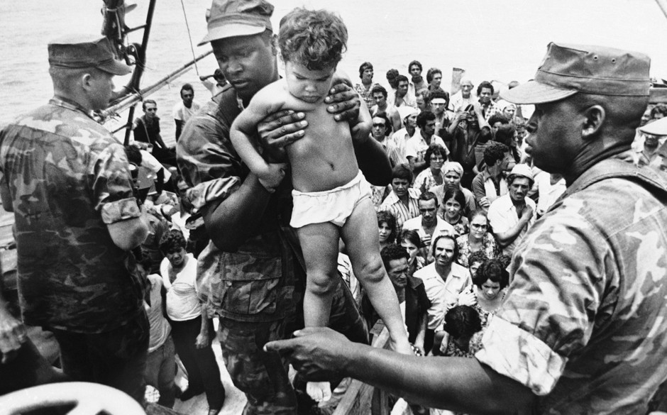 A U.S. Marine helps a young Cuban child off a refugee boat in Key West, Florida on May 10, 1980.
