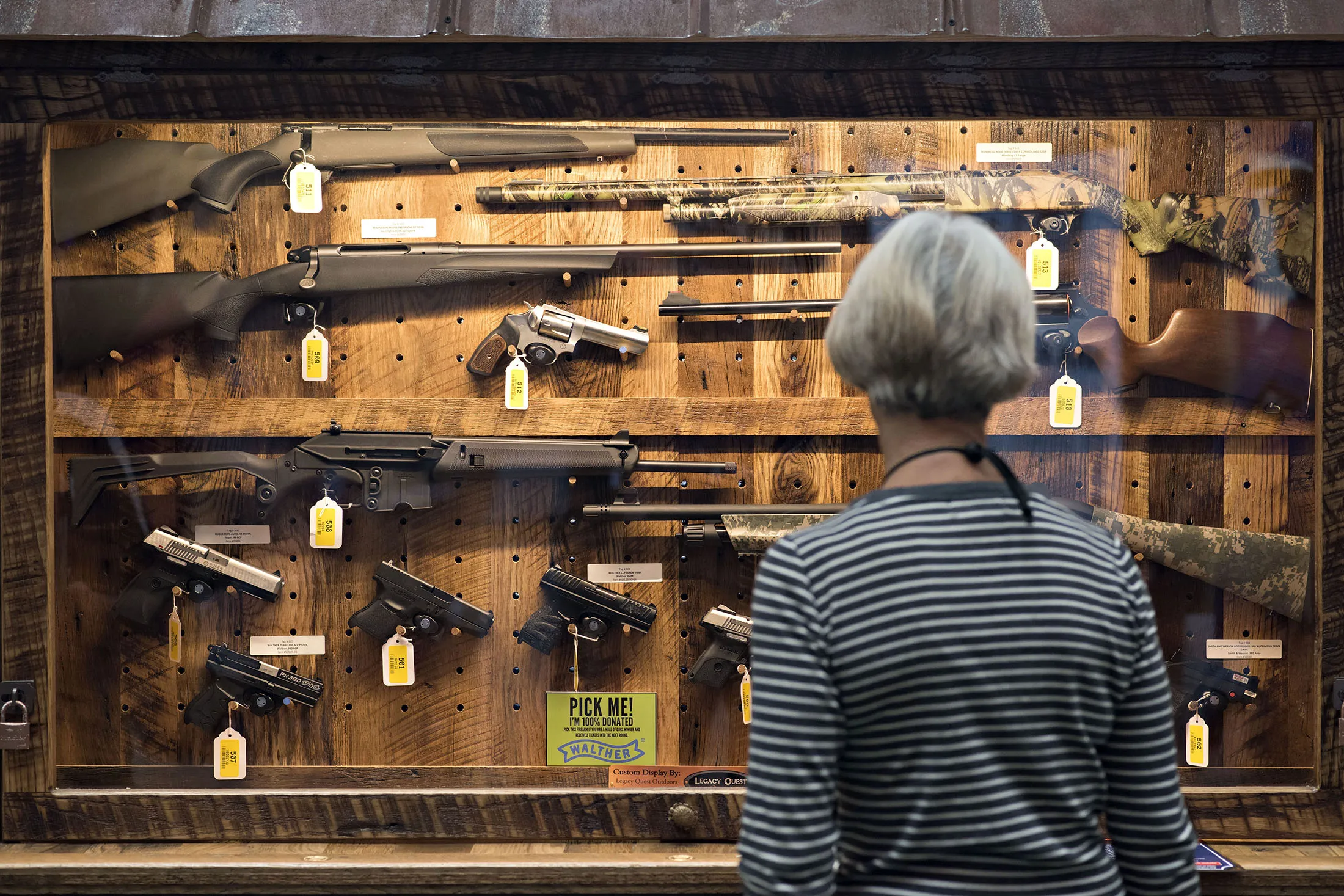 A woman looks over the 'Wall of Guns' raffle case during the 144th National Rifle Association (NRA) Annual Meetings and Exhibits at the Music City Center in Nashville, Tennessee, U.S., on Saturday, April 11, 2015. Top Republican contenders for their party's 2016 presidential nomination are lining up to speak at the annual NRA event, except New Jersey Governor Chris Christie and Kentucky Senator Rand Paul, who were snubbed by the country's largest and most powerful gun lobby.
