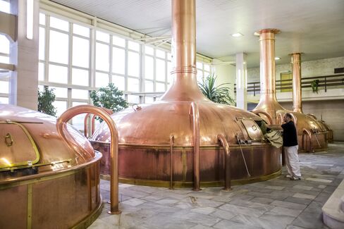 A technician adds hops to a fermenting vat of beer