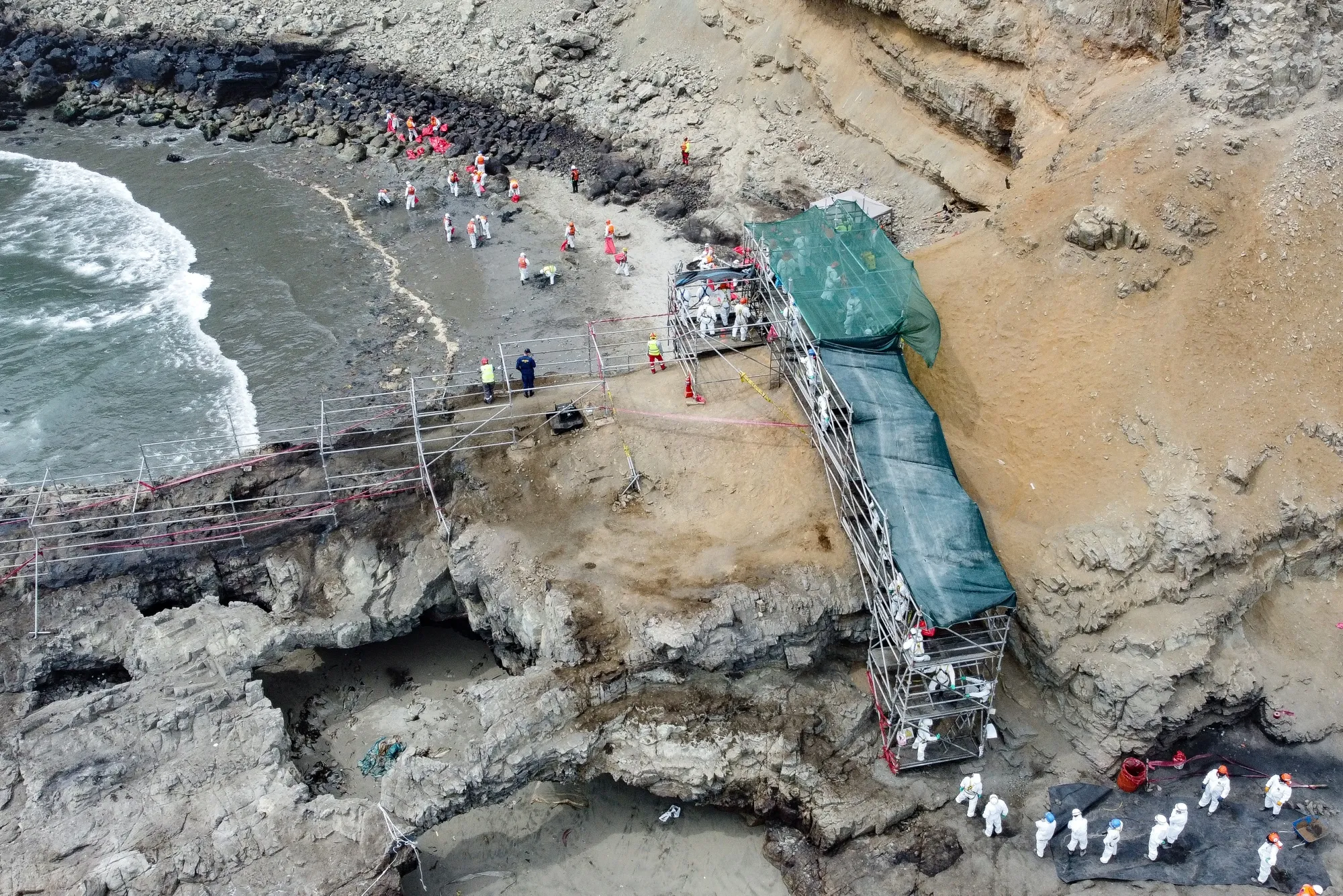 Workers clean Cavero beach following an oil spill in Callao, Peru, on Feb. 18, 2022.&nbsp;