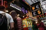 Pedestrians walk past a currency exchange store in Hong Kong, China.