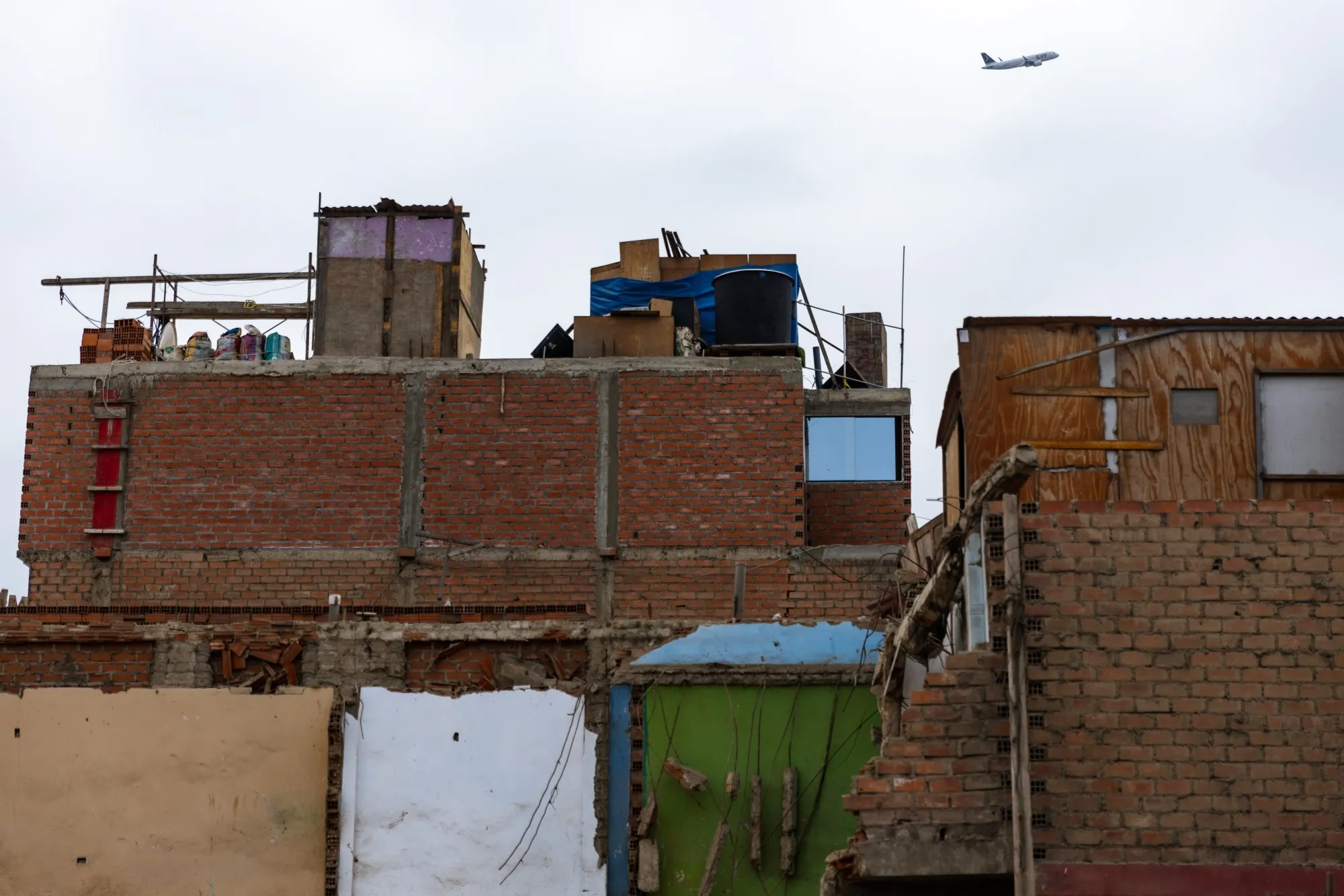 A airplane flies over a neighborhood near the new Jorge Chavez Airport (LIM) in Lima, Peru, on Wednesday, Dec. 18, 2024.