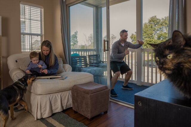 Mike Tilberry, owner of All In Coaching, center, leads a workout remotely at home in Myrtle Beach, South Carolina, U.S., on Saturday, Feb. 20, 2021. It's been a year since Covid-19 triggered the steepest economic collapse in modern U.S. history, with more than 22 million people thrown out of their jobs in a matter of weeks. Many have managed to find a way back to work.