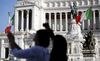 Tourists take photographs in front of a monument to the unknown soldier in Rome, Italy.
