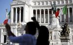 Tourists take photographs in front of a monument to the unknown soldier in Rome, Italy.