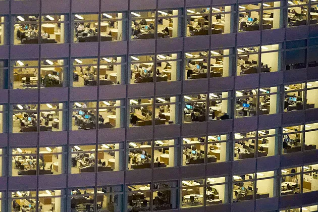 Night view of workers in an office building in the financial district in
New York City

