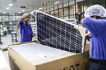 Employees place a solar panel into a box at a manufacturing plant in Bangalore, India.