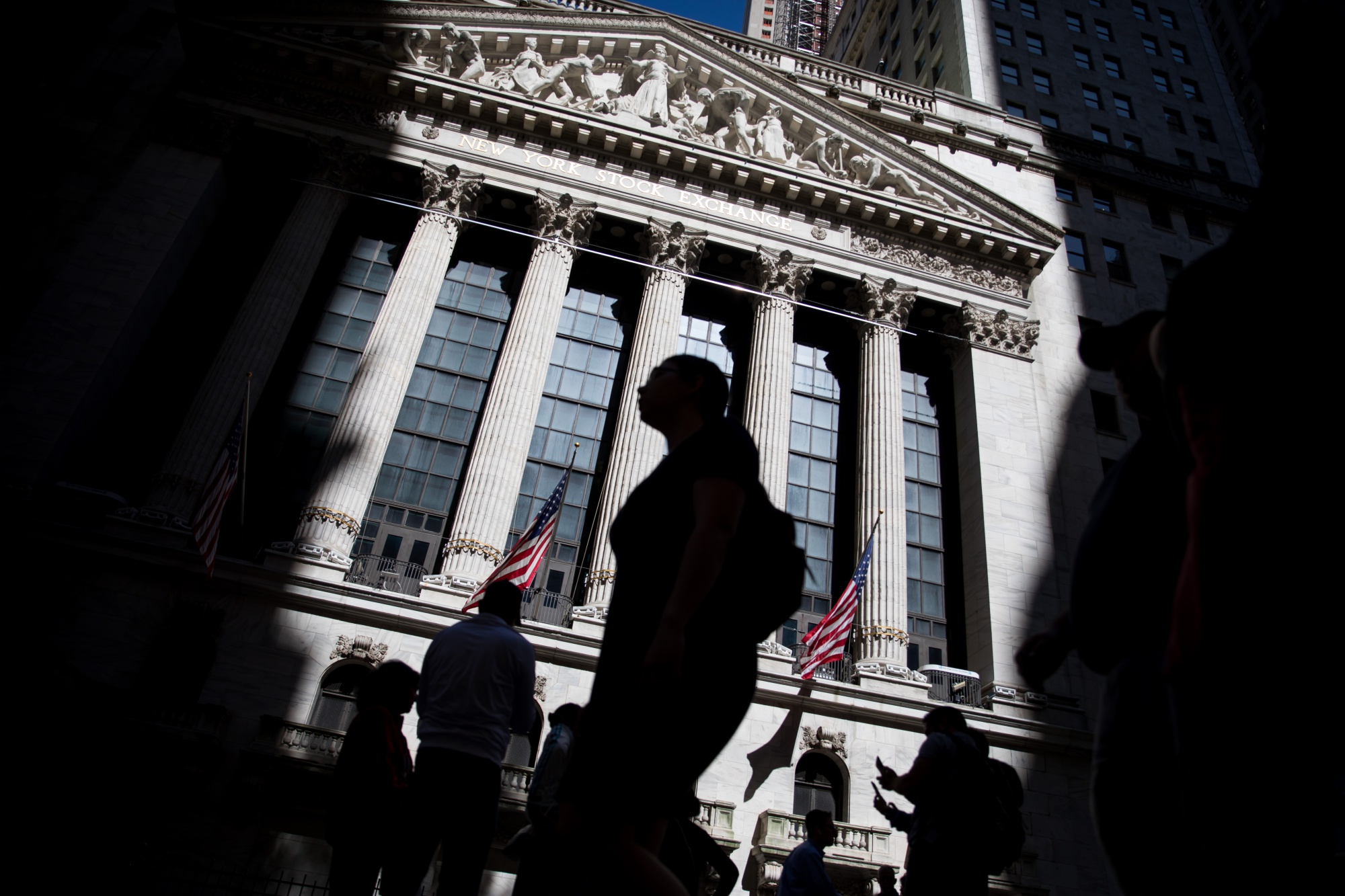 Pedestrians pass in front of the New York Stock Exchange (NYSE) in New York, U.S.