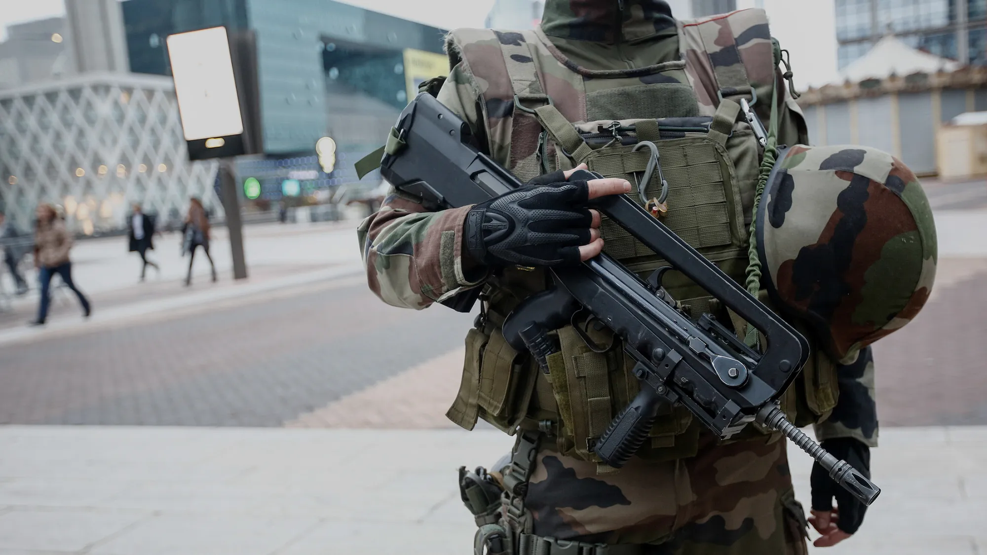 An armed member of the French armed forces stands guard as commuters make their way to work in Paris.

