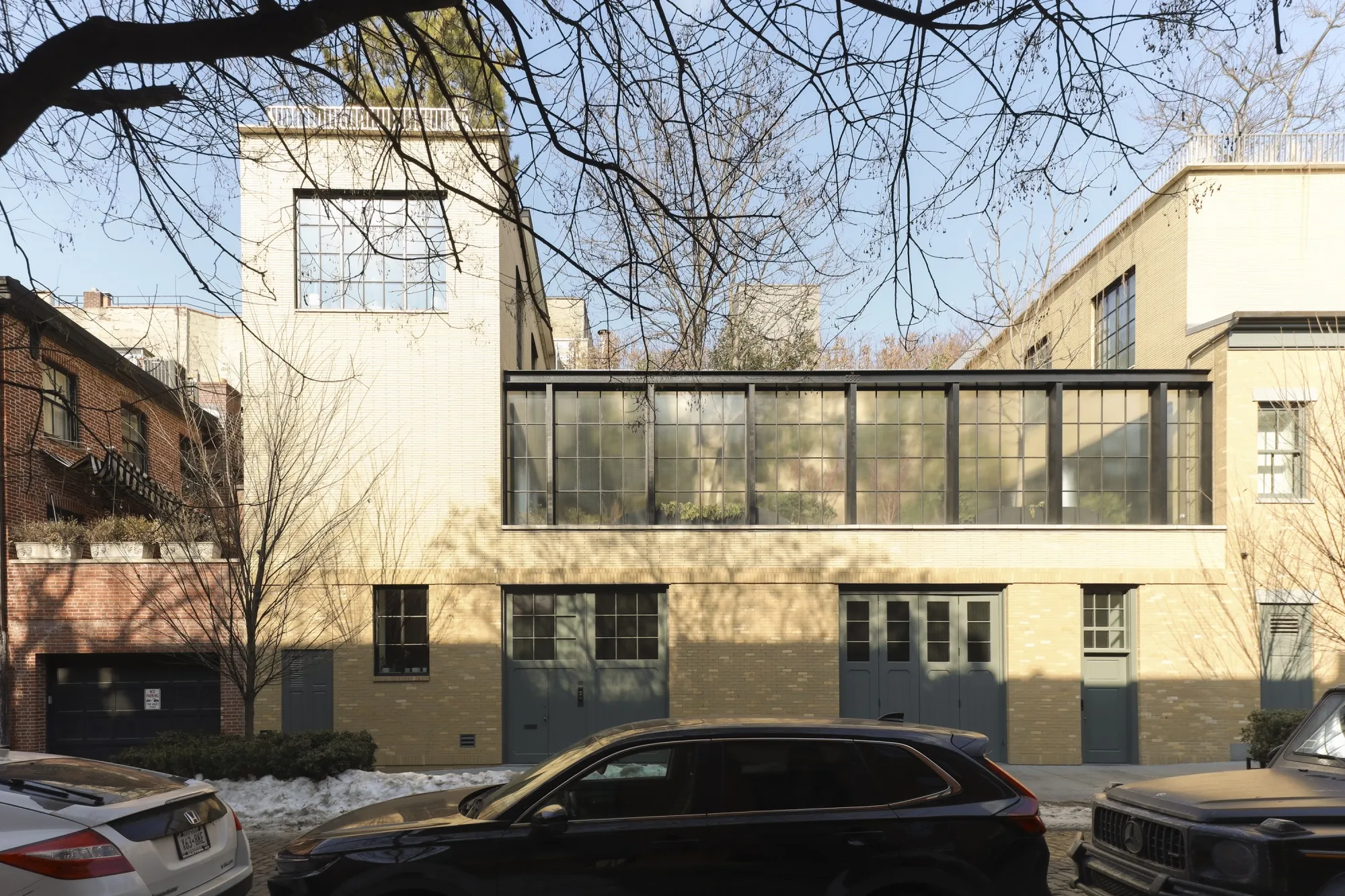 A beige brick mega-mansion with cars parked in front of it on the street.