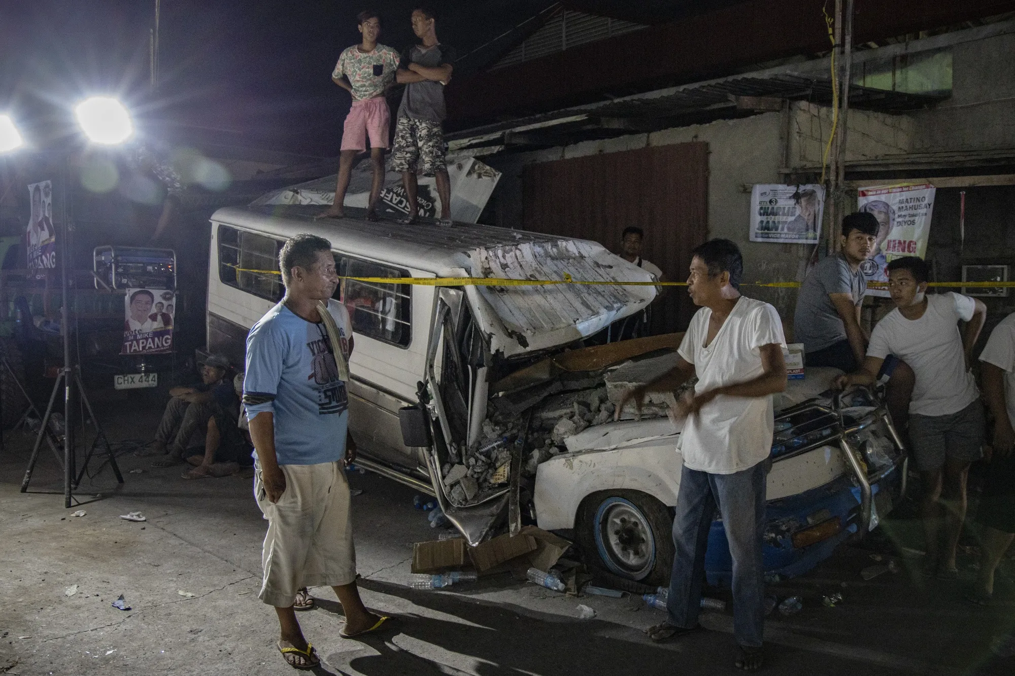 Onlookers watch next to a wrecked van as rescuers search for survivorsin Pampanga province, on April 23.