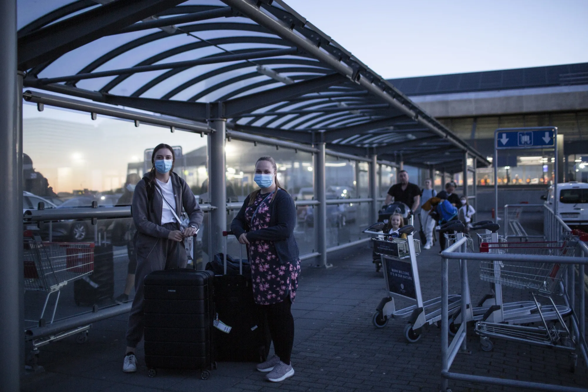 Travelers wearing protective face masks stand under a shelter after arriving at Keflavik International Airport on July 20.