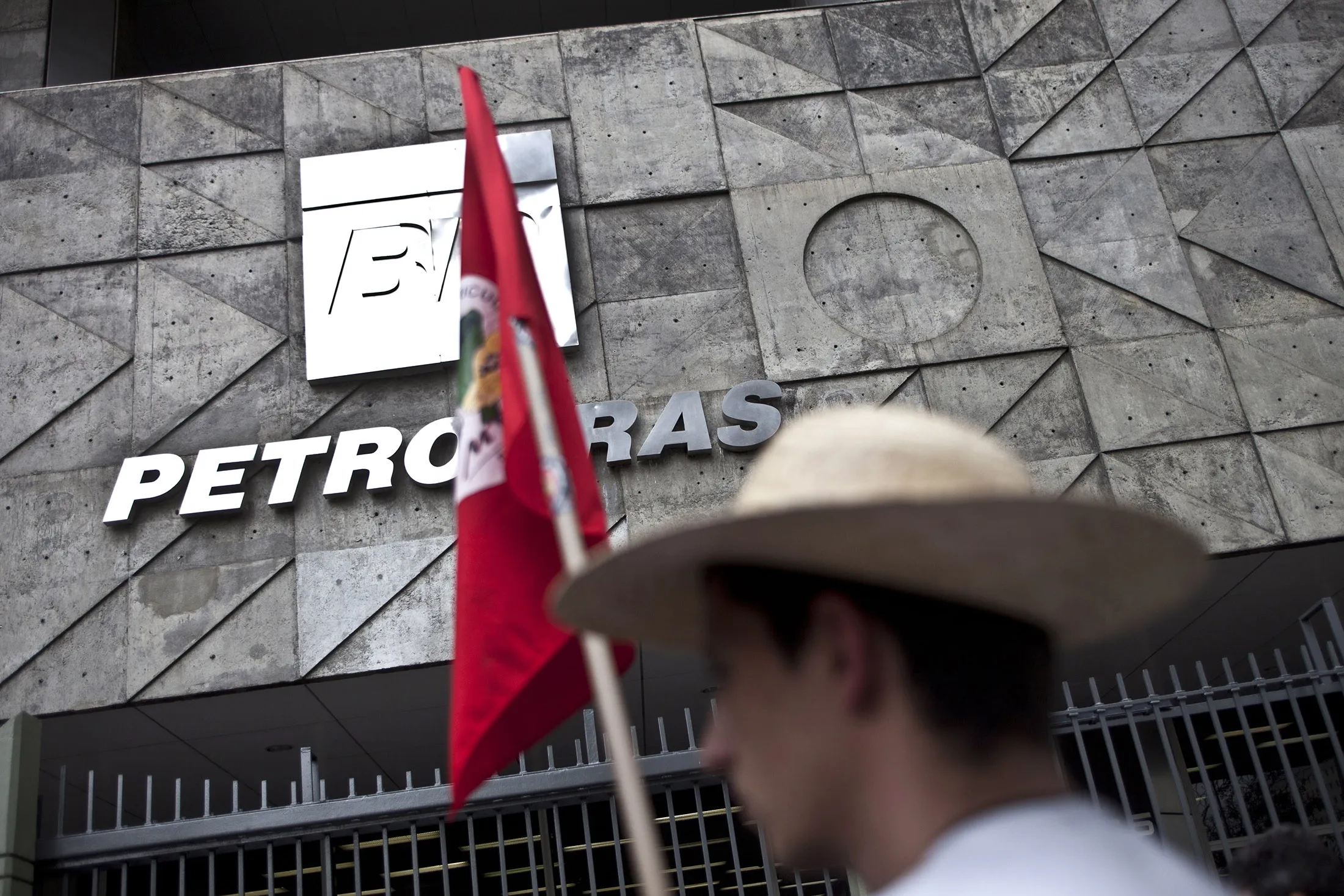 A demonstrator holds a flag during a protest against oilfield auctions outside the headquarters of Petroleo Brasileiro SA (Petrobras) in Rio de Janeiro, Brazil, on Oct. 17, 2013.
