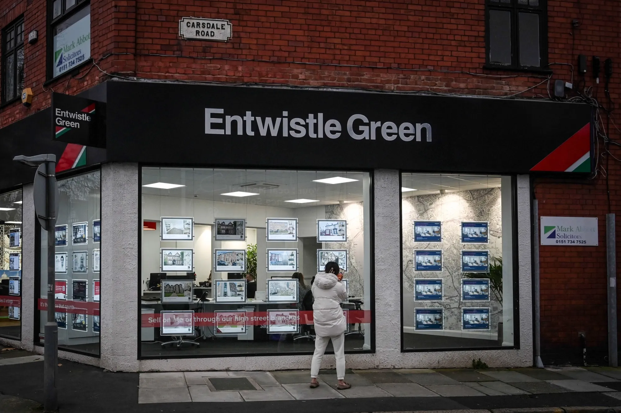 A pedestrian looks in the window of an estate agent in the Mossley Hill area of Liverpool, UK.