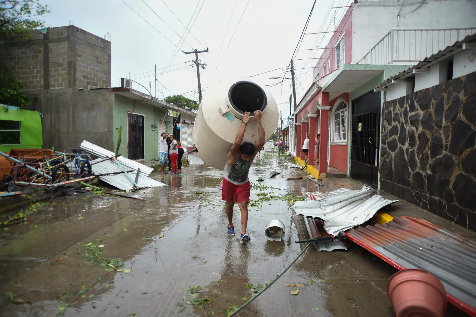A resident carries a water catchment tank past debris after Hurricane Grace made landfall in Tecolitla, Veracruz state, Mexico, on Saturday, Aug. 21, 2021.&nbsp;