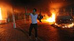his file photo taken on September 11, 2012 shows an armed man waving his rifle as buildings and cars are engulfed in flames after being set on fire inside the US consulate compound in Benghazi
