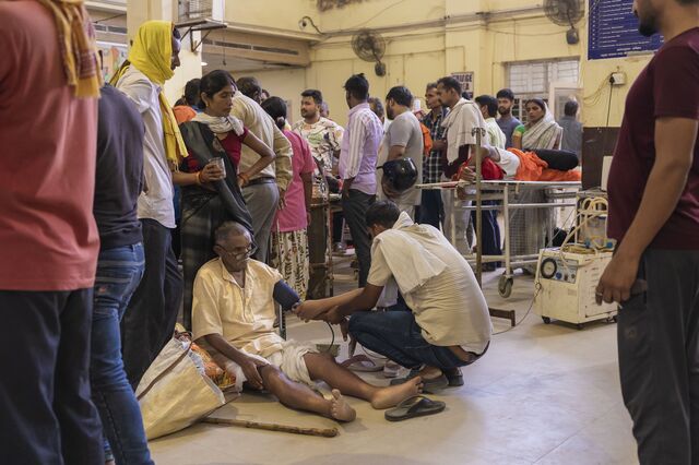 A son assists his father while the nurse checks on him