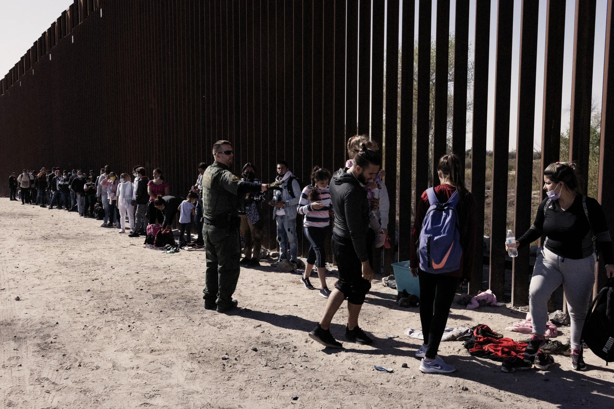 A U.S. Customs and Border Protection officer directs migrants seeking asylum into vans before transferring them to temporary shelters in Yuma, Arizona.