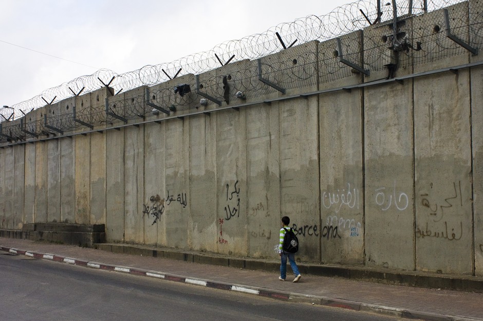 A boy walks home from school along the 26-foot-tall concrete Separation Barrier between al-Ram and Jerusalem.