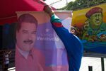A pro-government supporter hangs a campaign poster for Nicolas Maduro
