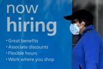 A woman wearing a face mask walks past a "Now Hiring" sign in front of a store in Arlington, Virginia.