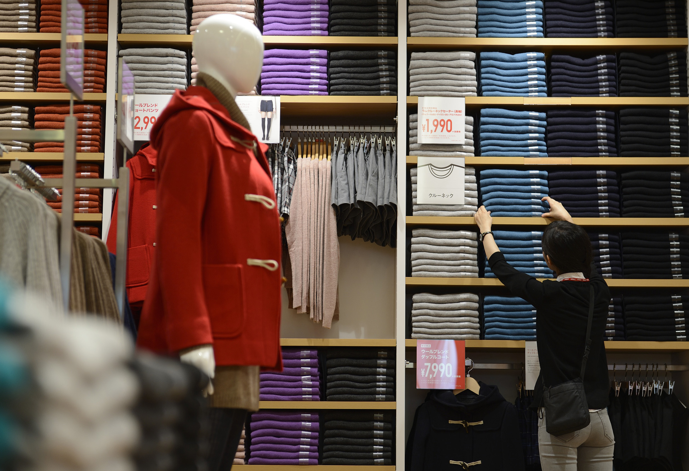 An employee arranges clothing for sale at a Uniqlo store in Tokyo, Japan.
