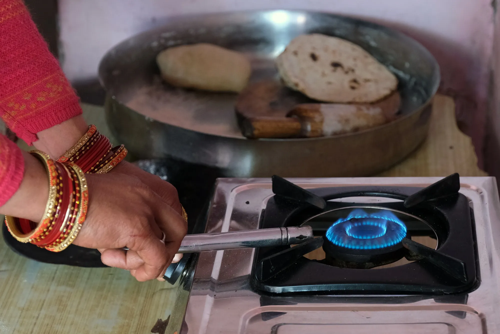 A woman lights a stove in India.