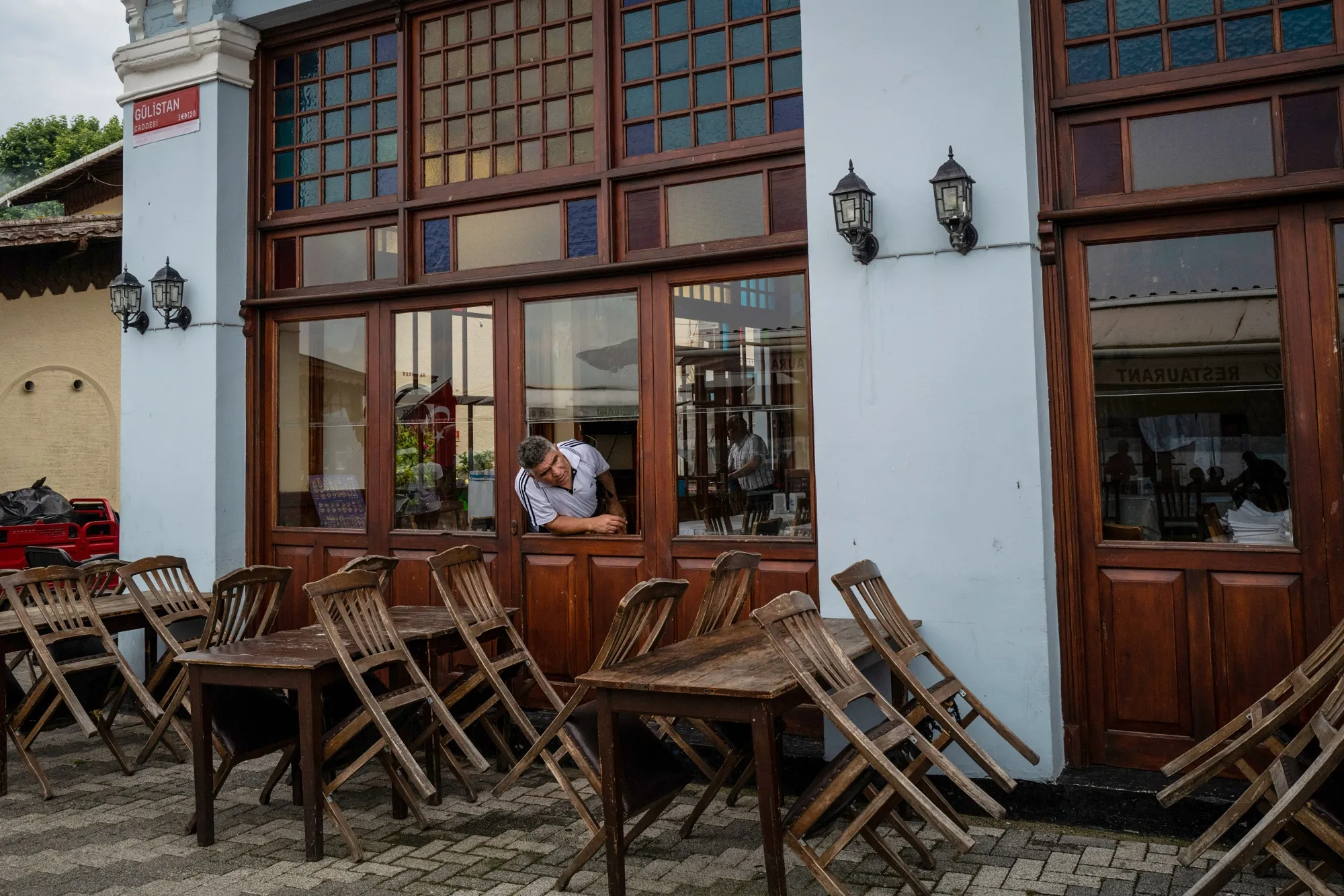 A&nbsp;restaurant worker looks out along the street by empty tables in Buyukada, Turkey, on June 23.&nbsp;
