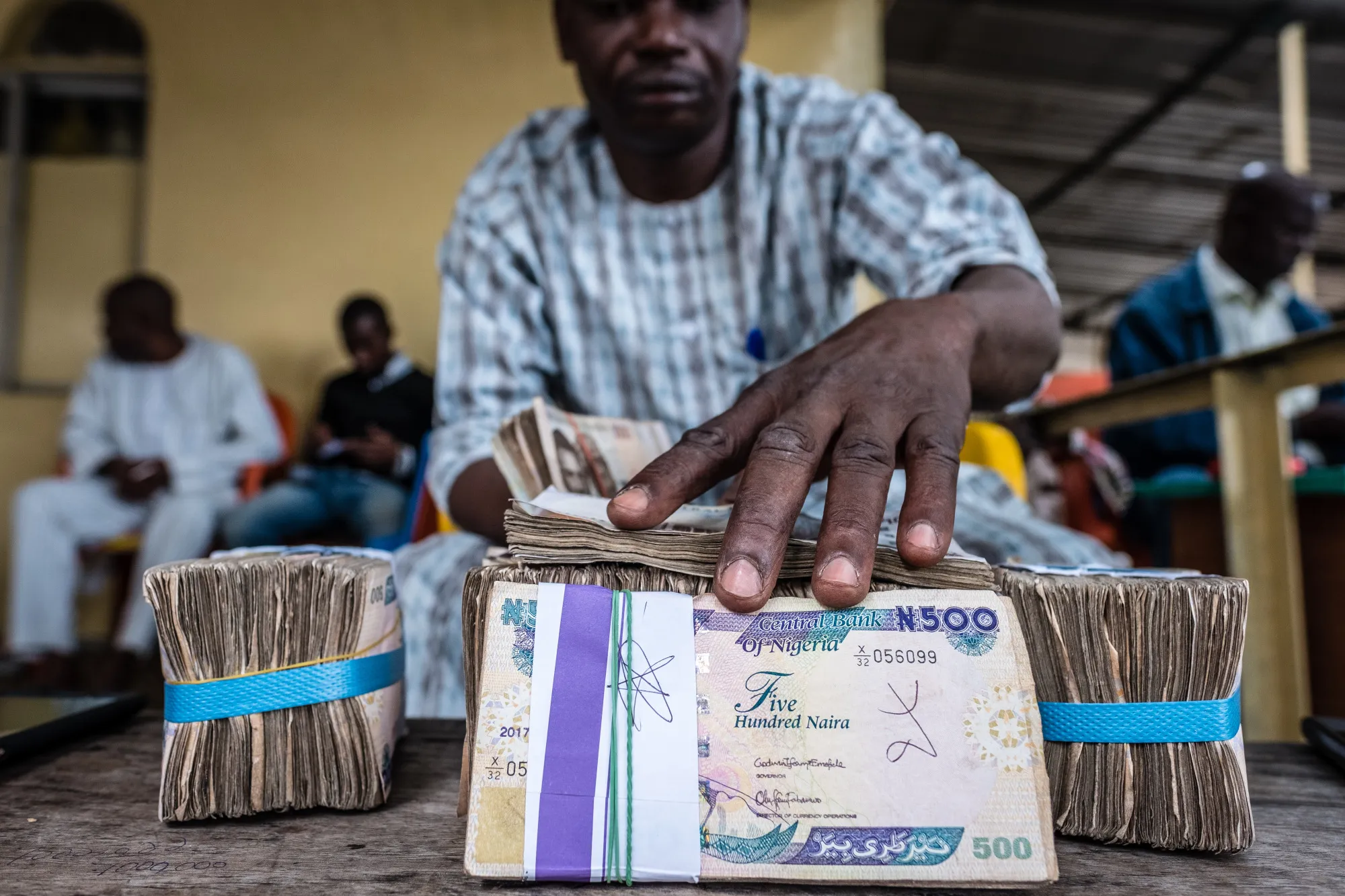 A currency dealer handles bundles of naira banknotes for exchange on the 'black market' in Lagos, Nigeria.