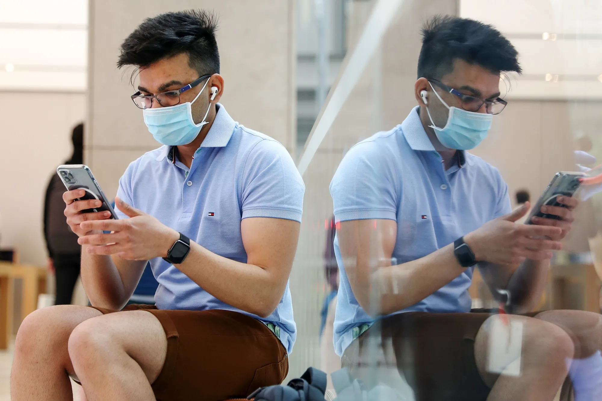 A customer wearing a protective mask tries out an&nbsp;iPhone at the Apple flagship store in Sydney.