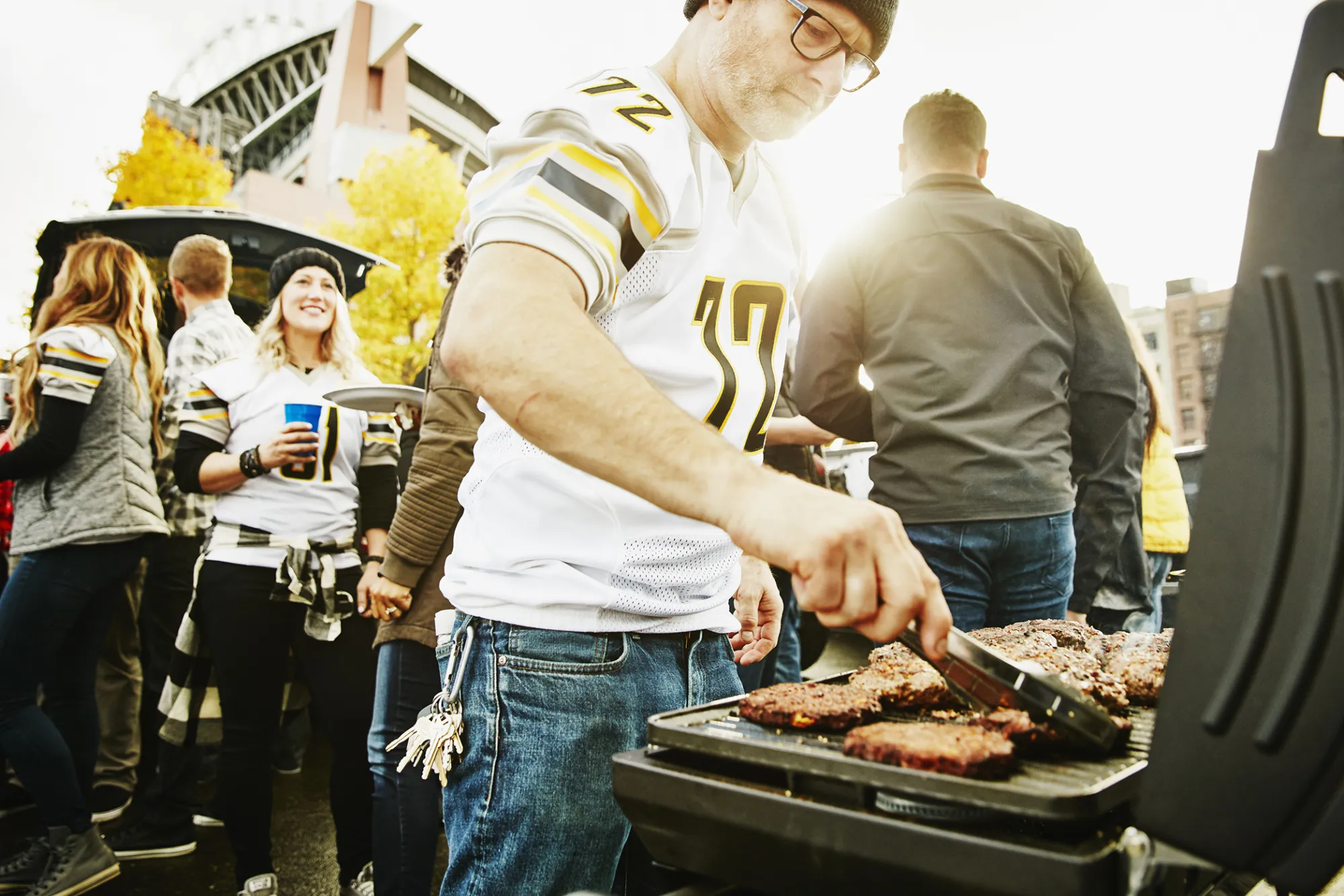 Man preparing food at barbecue for friends at tailgating party
