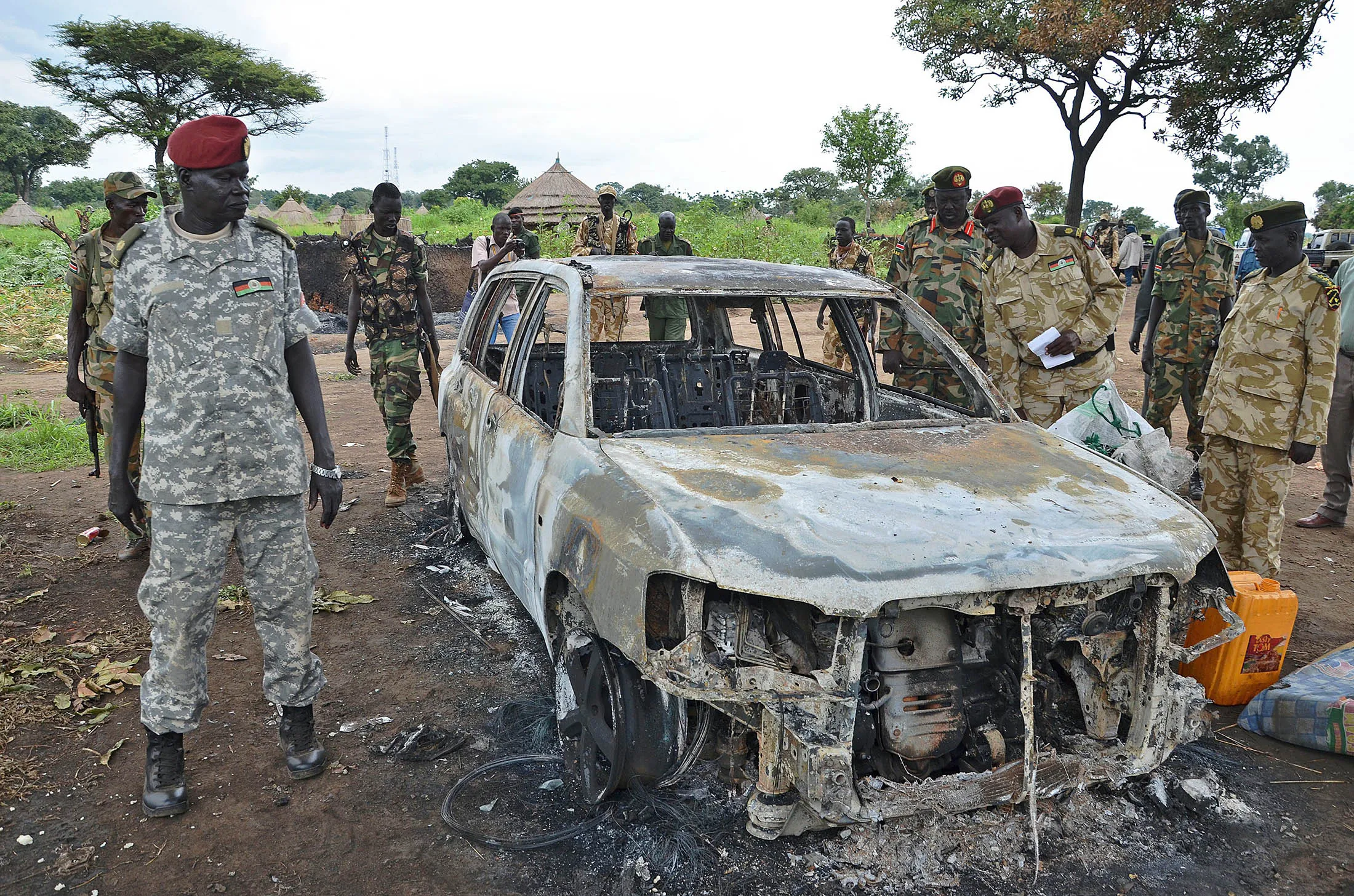 South Sudanese SPLA soldiers inspect a burned car in Pageri, Eastern Equatoria state, on August 20, 2015.
