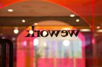 A colored glass wall is illuminated at the WeWork.