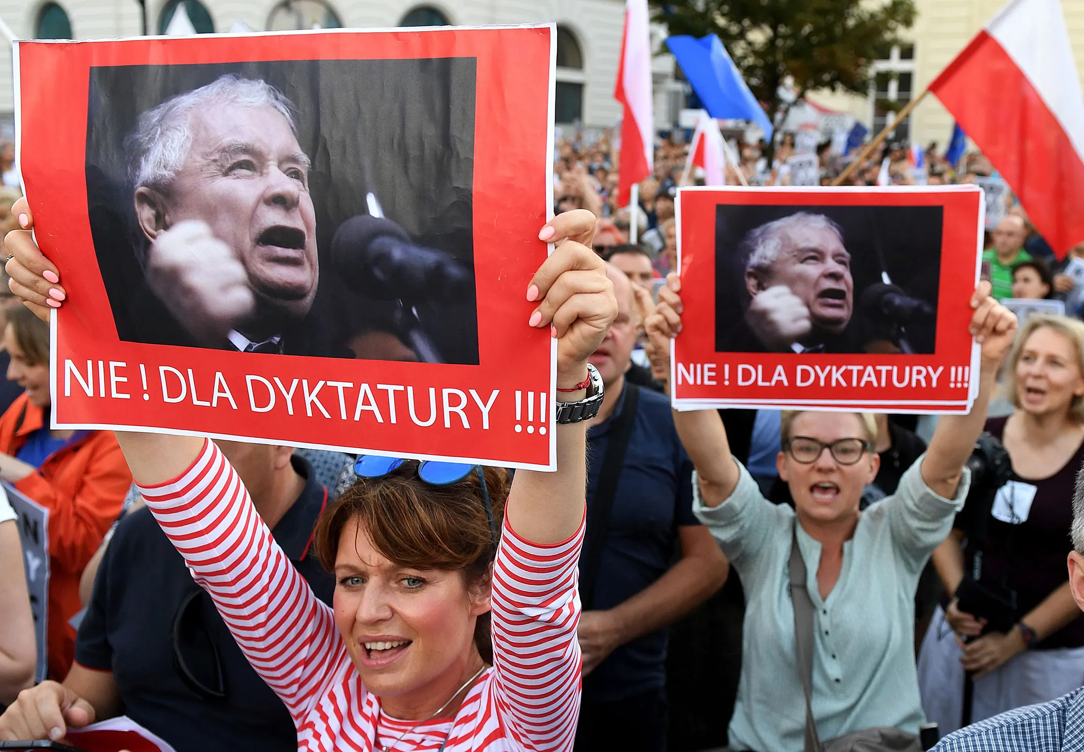 Protesters shout slogans and hold posters reading "No to dictatorship" during a protest in front of the presidential palace in Warsaw.
