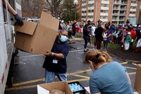 People wait in line to receive food distributed by Montgomery County Public Schools as part of a program to feed children while schools are closed in Silver Spring, Maryland, on March 20. 