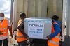 Two workers in orange vests carry a large box of Covax vaccines at the Ivato International Airport in Antananarivo, Madagascar, on May 8.