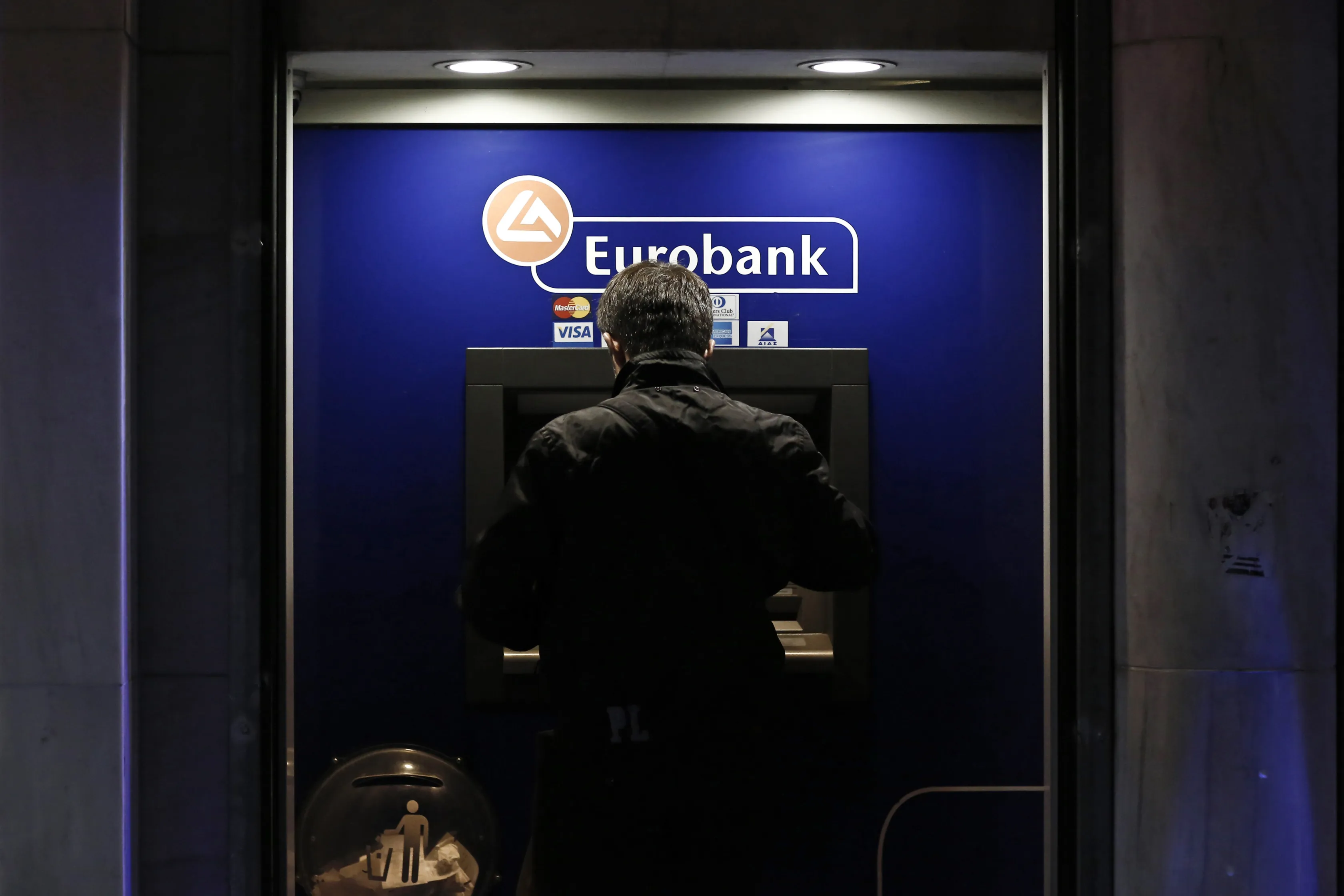 A customer uses an ATM&nbsp;operated by Eurobank Ergasias SA in Athens.&nbsp;