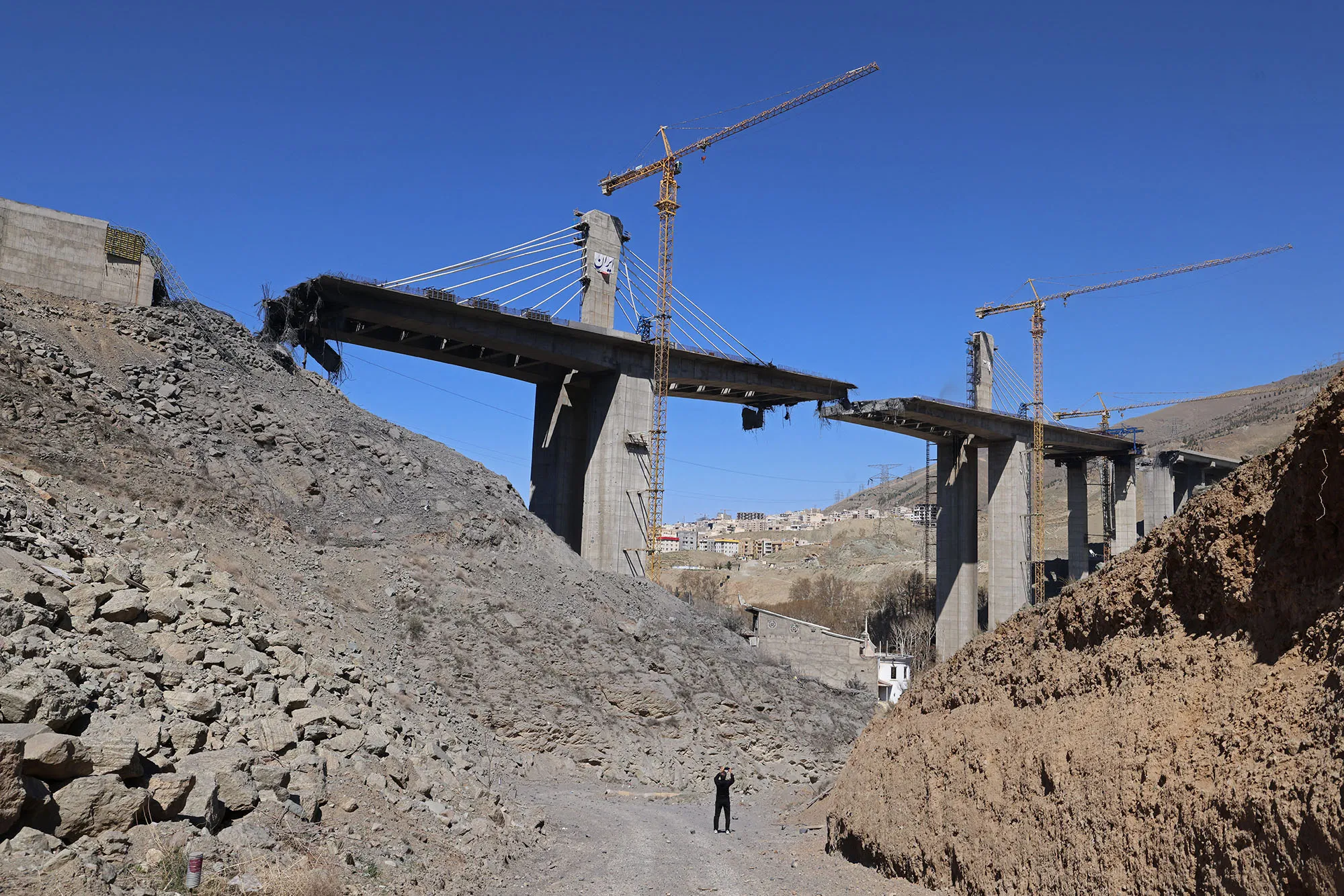 A man takes pictures of the B1 bridge a day after it was destroyed by an airstrike in Karaj, Iran, on April 3.