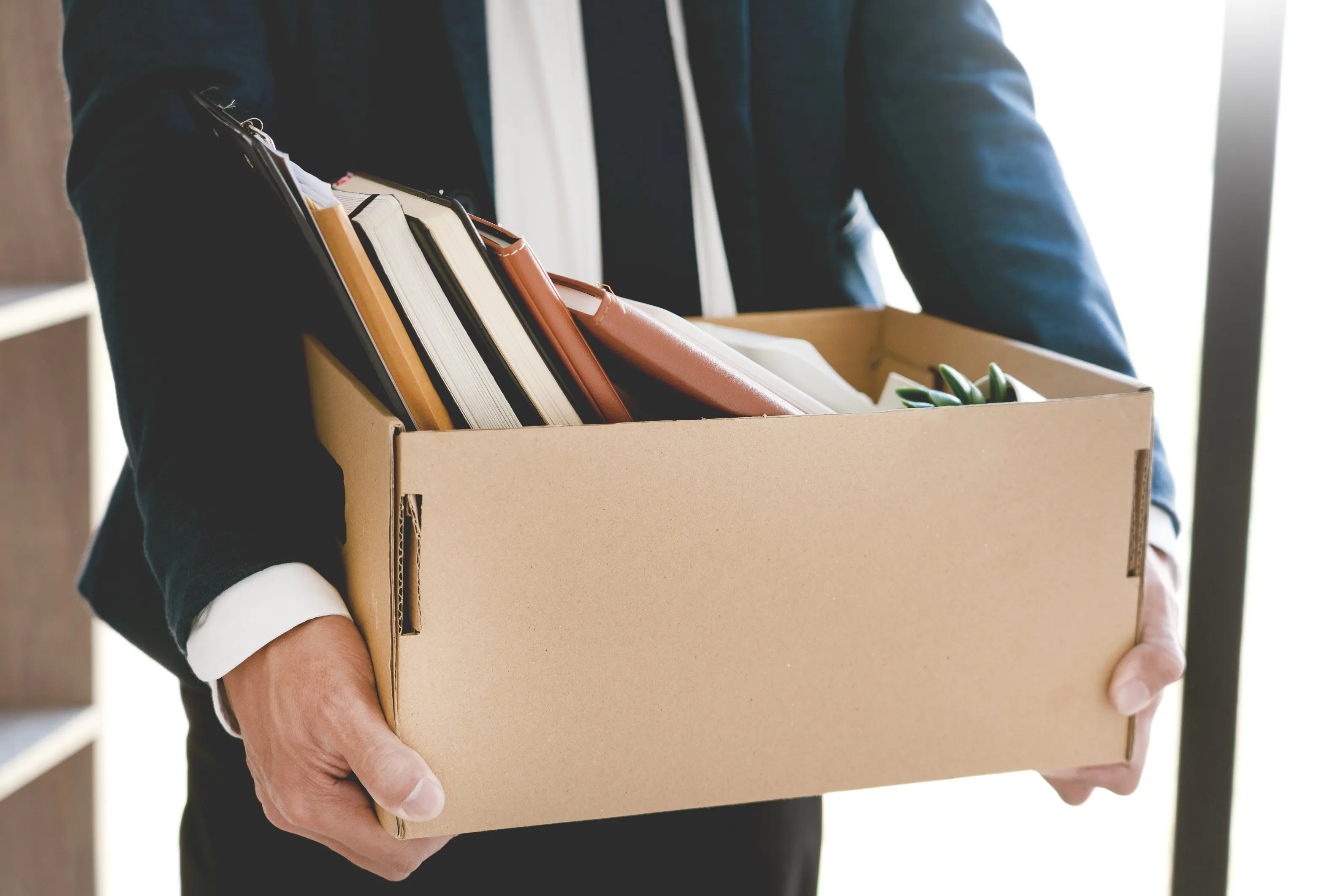Midsection Of Businessman Carrying Cardboard Box In Office