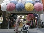 An elderly woman walks past an umbrella shop in Tokyo.