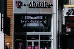 Pedestrians pass in front of a T-Mobile US Inc. store in New York, U.S.