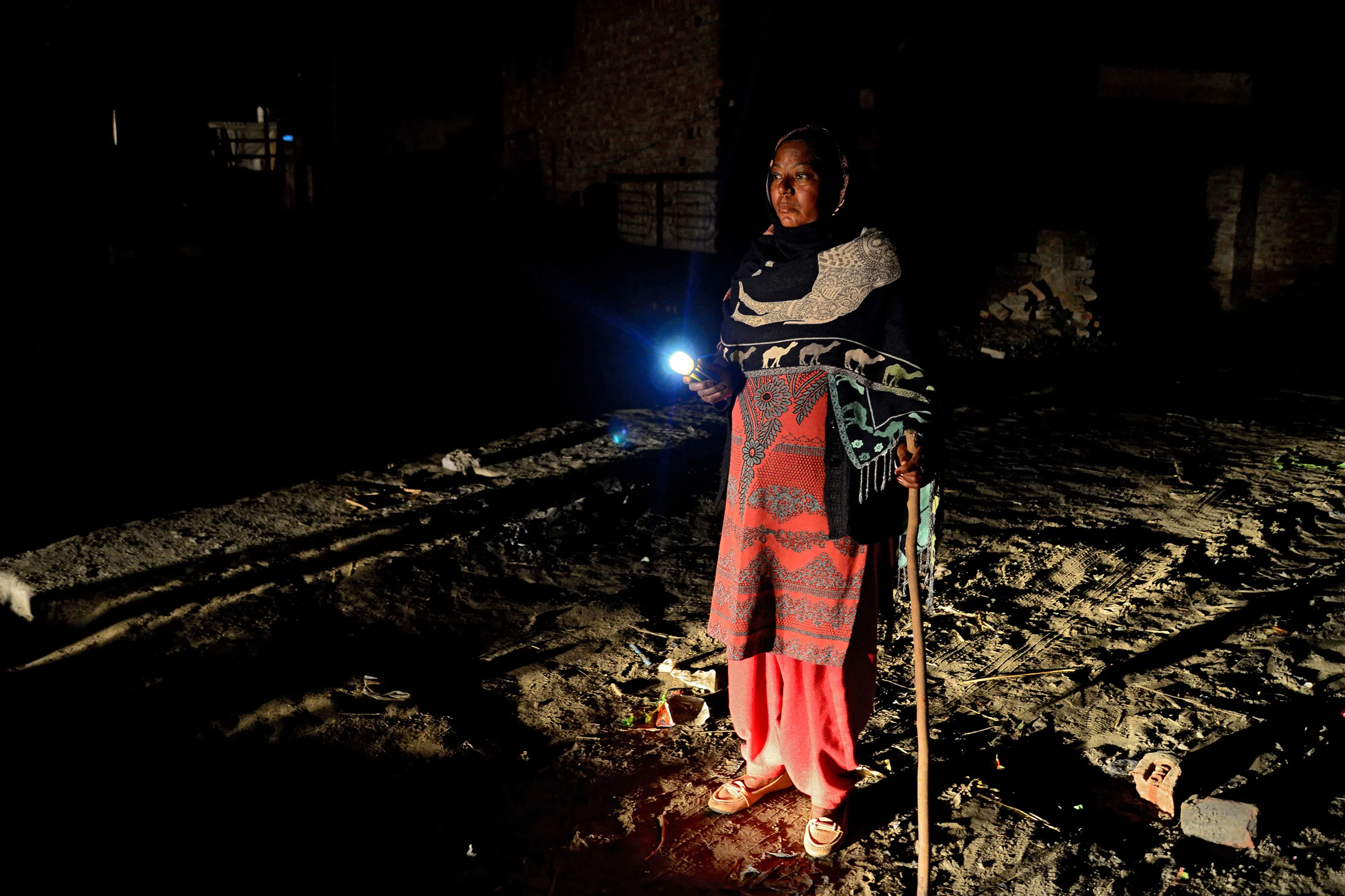 A watchwoman, walks with a flashlight during her night round at Bhangiwal village near Mehatpur.