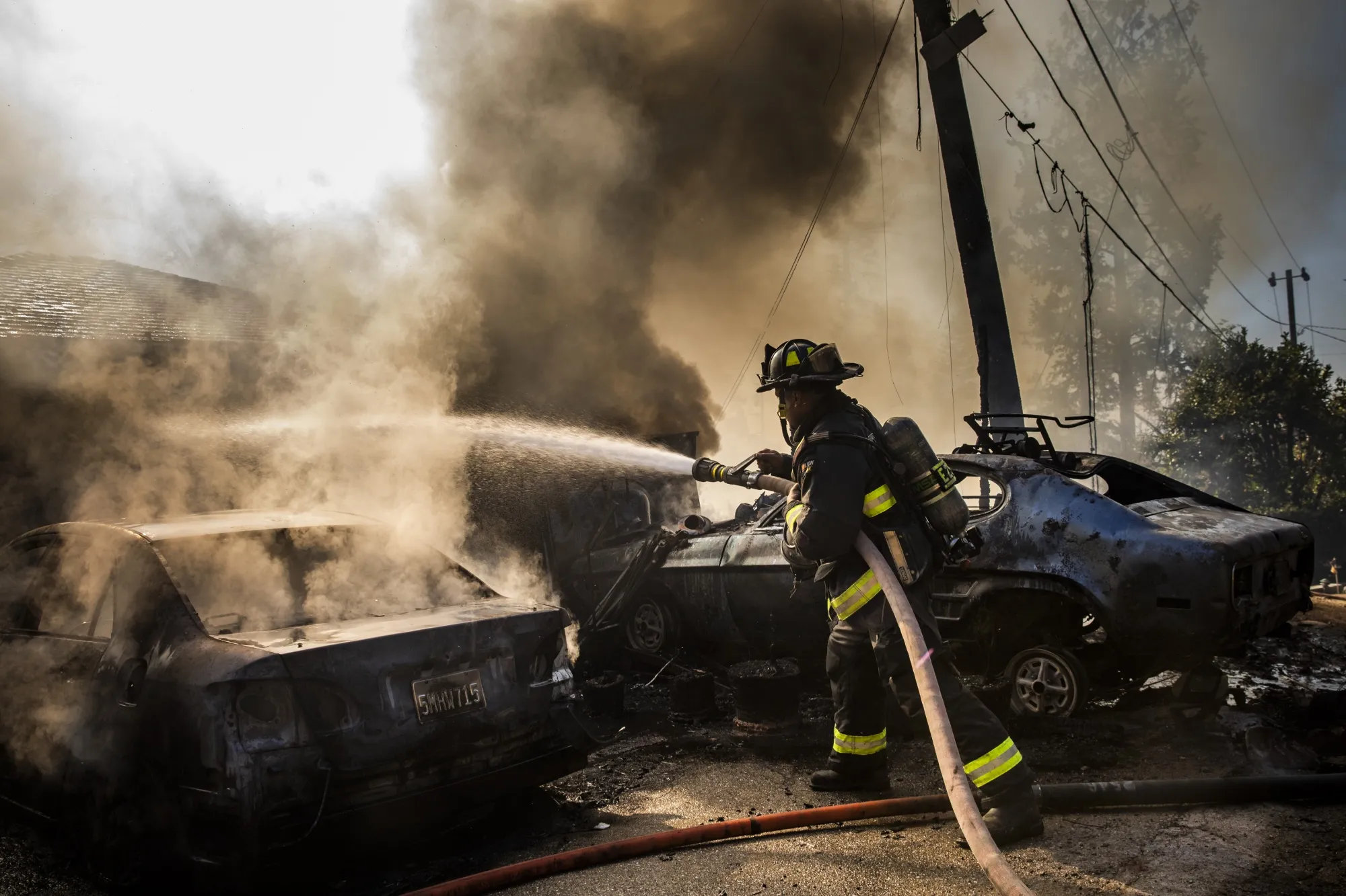 A firefighter extinguishes a structure fire in the Montclair Hills neighborhood of Oakland, California, in Oct. 2020. The preliminary cause of the fire was an overloaded generator. PG&amp;E cut power in the area to prevent live wires from falling into dry brush during the wind storms.
