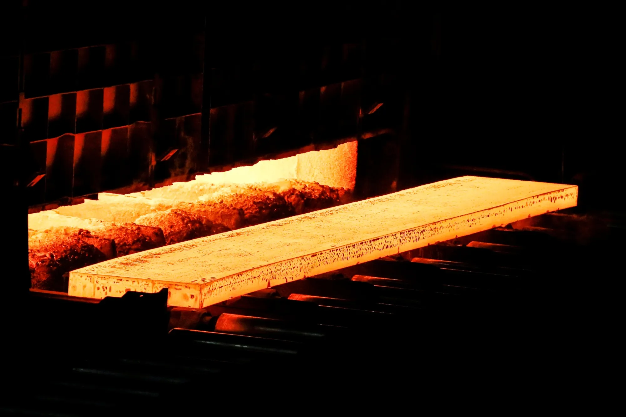 A red-hot steel slab in a rolling mill.