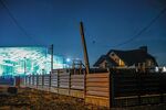 The lights of the Olympic media center near the Black Sea coast illuminate a neighboring residential building
