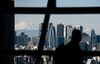 Mount Fuji stands beyond buildings as a visitor looks out at the skyline from an observation deck in Tokyo, Japan, on Friday, Jan. 11, 2019. Japan’s key inflation gauge slowed in the first back-to-back decline since April, highlighting the difficulty of the Bank of Japan’s price goal ahead of its policy meeting next week.